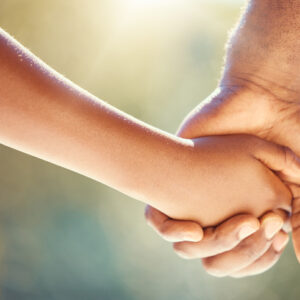 Trust, family and adoption with father and child holding hands while walking together outside. Parent and son showing security, care and love with man and boy sharing a safe and special bond