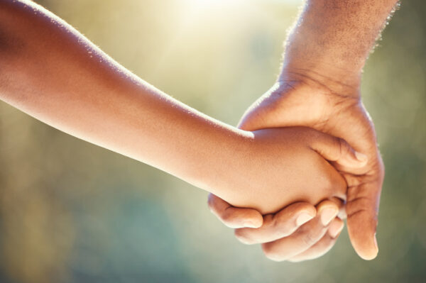 Trust, family and adoption with father and child holding hands while walking together outside. Parent and son showing security, care and love with man and boy sharing a safe and special bond