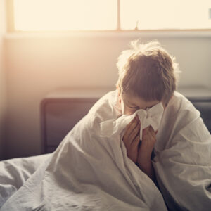 Portrait of sick little boy aged 8 lying in bed. Nikon D850