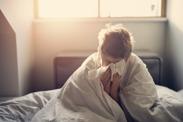 Portrait of sick little boy aged 8 lying in bed. Nikon D850